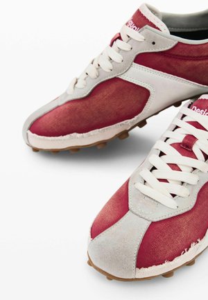 Pair of red and white athletic shoes with white laces and textured brown soles, shown from angled top and side views.