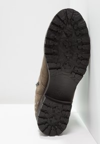 Hnědá nubuková bota s texturovanou černou gumovou podrážkou s hlubokými jemnými vzory a dekoračními kovovými akcenty po straně. Velikost 37.