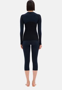 Dunkelblaue Langarmoberteil mit taillierter Passform und passenden 3/4-Leggings, die über strukturierte Akzente an den Beinen verfügen. Glattes, dehnbares Material.