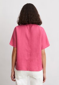 Kurzarm, pinkes Leinenhemd mit geradem Schnitt, einfarbiger Textur und mittigem Nahtdetail, entworfen für eine lässige Passform.