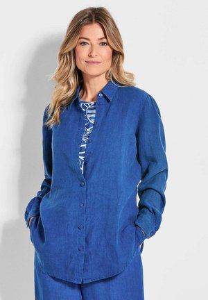 Chemise en lin bleu à boutons, avec col, manches longues et coupe décontractée ; présente de petits boutons et une surface texturée.
