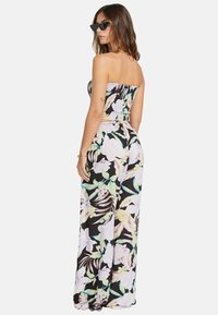 Jumpsuit nera senza spalline con corpetto smock, caratterizzato da grandi fiori pastello e motivi di foglie, gambe ampie e tessuto leggero.