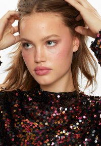 Top nero in paillettes con scollatura alta, adornato da paillettes circolari in tonalità di rosa, oro e rosso, creando una superficie riflettente e texturizzata.