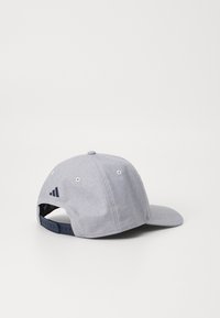 Căciulă gri cu o umbrelă curbată, realizată dintr-un material texturat. Prezintă un logo brodat de culoare albastru închis și închidere ajustabilă tip snapback.