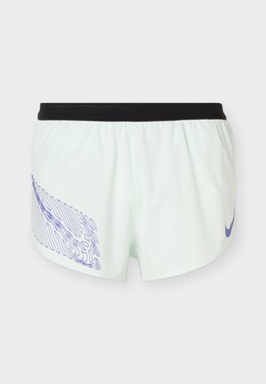 Biele športové šortky s čiernym pásom, s fialovým abstraktným vzorom na ľavej nohe a fialovým logom Nike na pravej nohe.