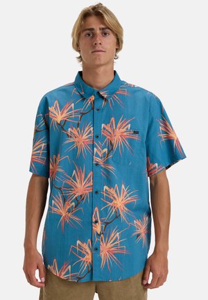 Camisa de manga corta hecha de tela azul con un patrón floral tropical en naranja y amarillo, con cierre de botones en la parte delantera y cuello.