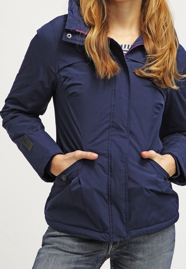 Giacca isolante di colore blu navy con chiusura a zip frontale, cappuccio e due tasche laterali. Presenta una texture liscia e un delicato dettaglio di fodera interna.