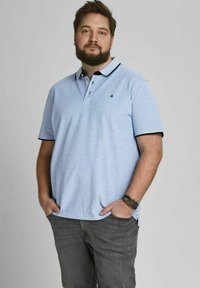 Lichtblauwe polo shirt met een zwarte kraag en een twee-knopenrij. Draagt u met grijze jeans, met een relaxte pasvorm.