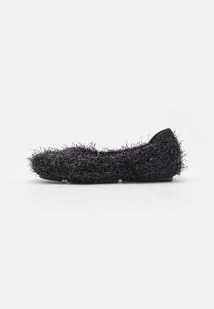 Chaussure extérieure noire avec une surface moelleuse et texturée dotée de fibres allongées, un design bas et un accent noir uni au niveau du talon.