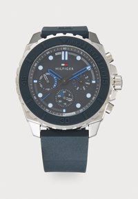 Reloj cronógrafo con una correa de silicona texturizada de color azul oscuro, esfera azul marino, acentos plateados y detalles azules en los marcadores de hora y las manecillas.