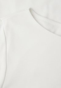 Camiseta blanca de algodón con textura acanalada, que presenta un escote redondo y mangas cortas, mostrando una costura limpia alrededor de los bordes.