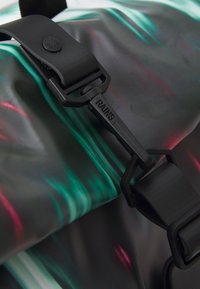 Svart vattentålig ryggsäck med färgglada, vågiga mönster i grönt och rosa. Har ett robust svart plastspänne och en mönstrad rem.