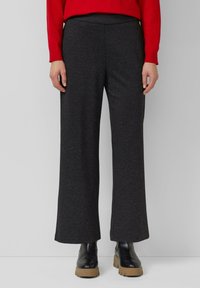 Dunkelgraue, weite Hosen aus weichem Stoff mit hoher Taille und ohne sichtbare Verschlüsse. Kombiniert mit schwarzen Stiefeletten.