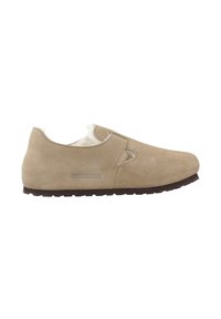 Zapato slip-on de ante beige con recortes y suave forro blanco, con una suela de goma oscura. "Birkenstock" impreso en el lateral.