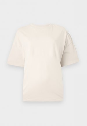 T-shirt uni à manches courtes couleur blanc cassé avec un col rond, présenté sur un fond gris clair neutre.