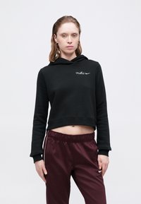 Melnā īsā kapuce, kas izgatavota no mīkstas materiāla ar kapuci, ar baltu izšūtu "nike" logo. Apvienota ar bordo elastīgiem vidukļa sporta biksēm.