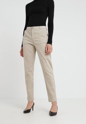 Béžové kalhoty s přizpůsobeným střihem, vybavené předním zapínáním na knoflíky, bočními kapsami a hladkým bavlněným materiálem. Kombinováno s černými lodičkami.