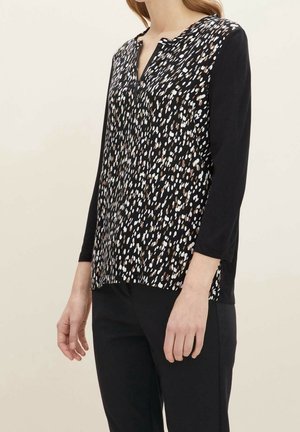 Top estampado con una mezcla de puntos en negro, blanco y marrón, con mangas tres cuartos y un diseño de escote en V. Material ligero.
