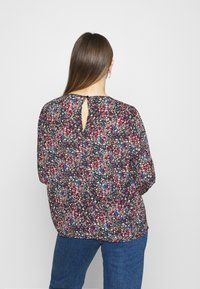 Blommig blus på mörk bakgrund med flerfärgade blommönster. Knappslå med nyckelhål bak. Löst sittande ärmar, lättviktsmaterial.