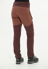 Mörkröda friluftsbukser med en åtsittande design, med kontrasterande khaki-paneler, fickor med dragkedja och förstärkta nederdelar.