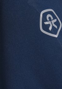 Marineblått stoff med en teksturert overflate som har en lys grå geometrisk logo i øverste høyre hjørne.