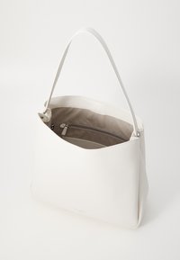 White leather tote bag with a structured shape, soft texture, and a single shoulder strap. Interior features a zip pocket and neutral lining.