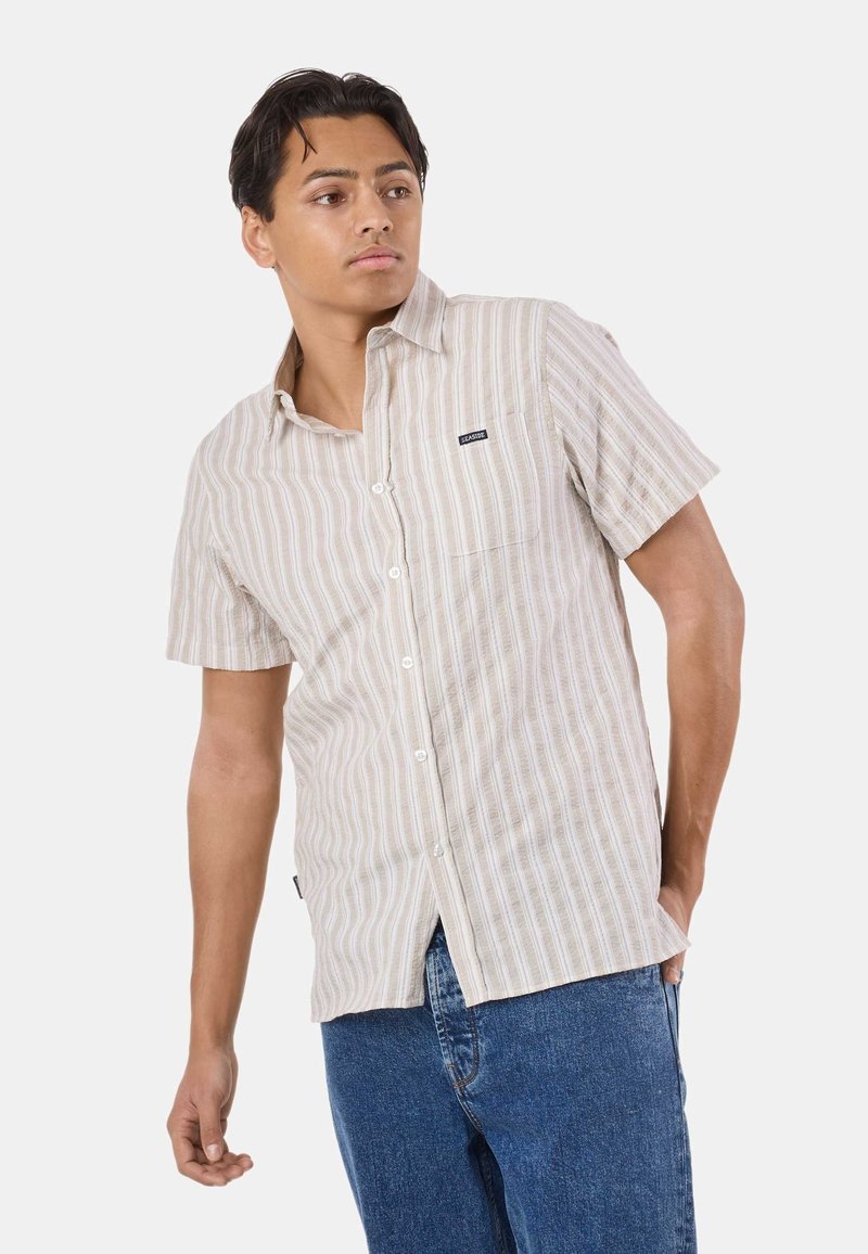 Chemise à manches courtes rayée en beige clair et crème, dotée d'un design à boutons, d'un tissu doux, et d'une poche poitrine gauche.