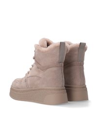 Beige suède enkellaarzen met een gestructureerde plateauzool, nepbont voering en een trekstrip aan de achterkant. Gedetailleerde stiksels zichtbaar aan de zijkanten.