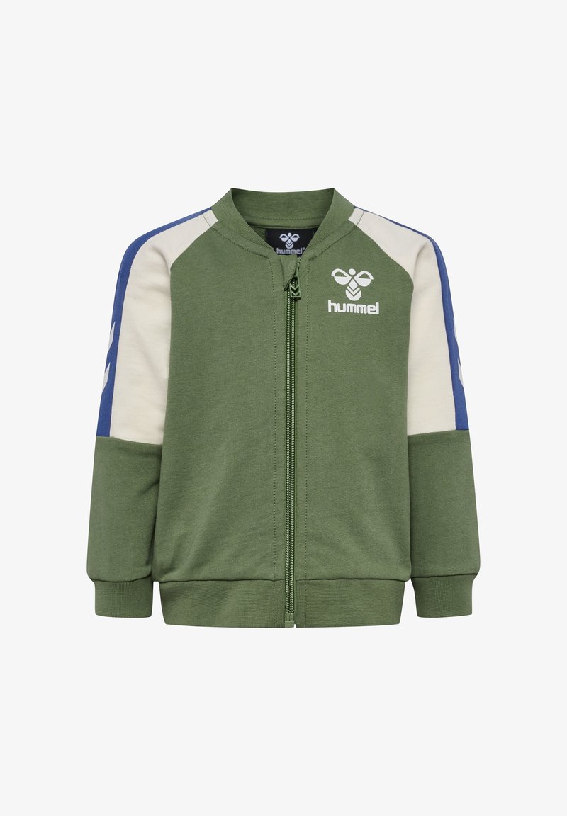 Veste à zip verte avec accents bleus et crème, poignets et ourlet côtelés. Présente le logo Hummel sur la poitrine et un design sportif. Fabriquée en tissu doux.