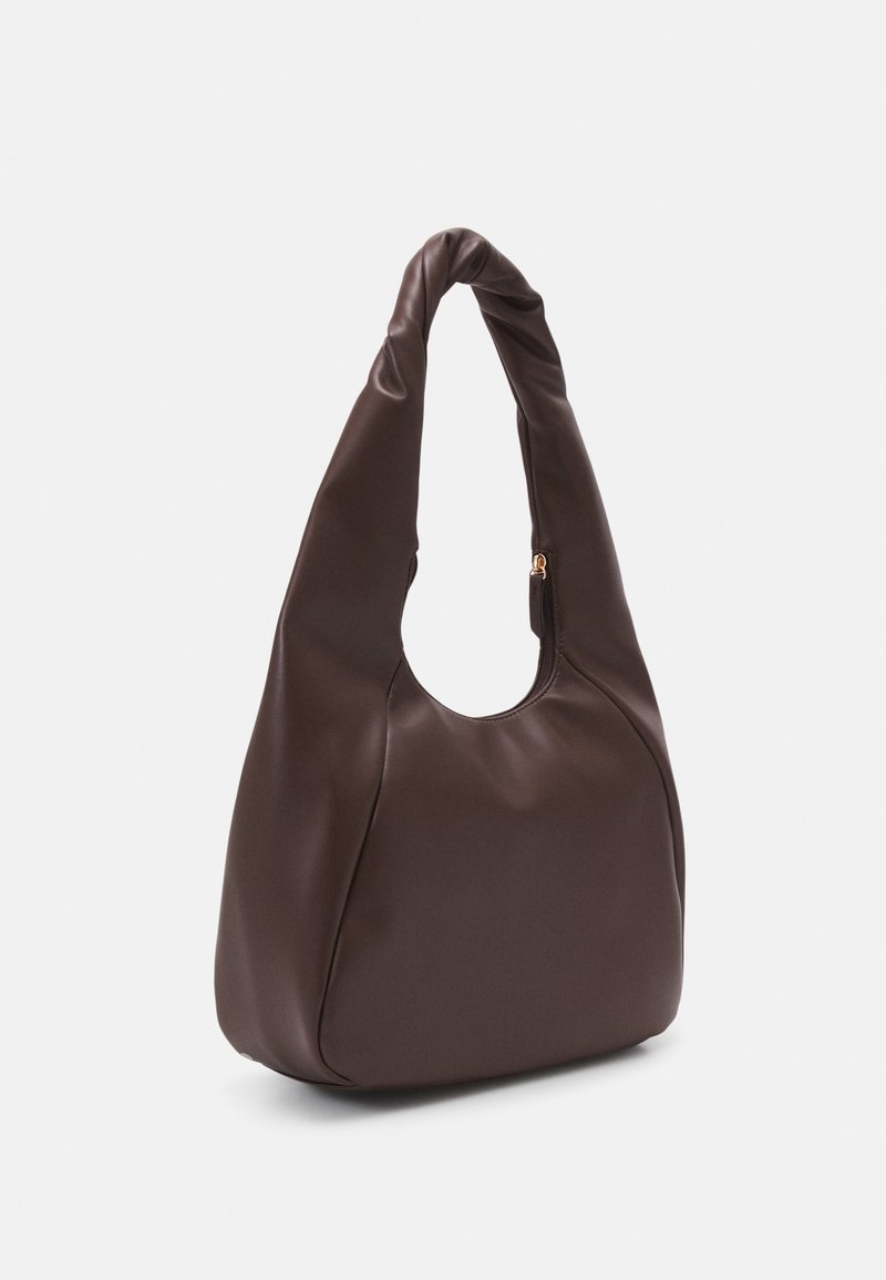 Borsa a mano in pelle marrone con una texture liscia, forma arrotondata e una tracolla intrecciata. Presenta una chiusura zip e dettagli di cucitura minimali.