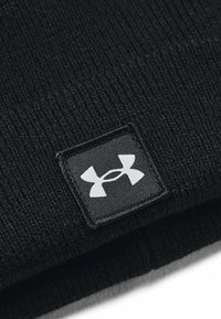 Berretto lavorato a maglia nero con un motivo testurizzato e una prominente etichetta del logo Under Armour bianca sul davanti.