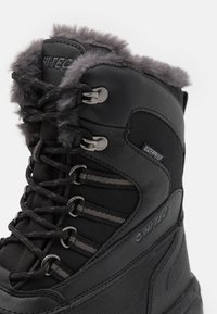 Schwarze wasserdichte Stiefel mit Kunstfellbesatz, strukturiertem Leder- und Stoffobermaterial, Metallschnürösen und grauen Schnürsenkeln. Verfügt über ein Logo und ein verstärktes Design.