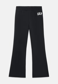 Melnas platu kāju sporta bikses, izgatavotas no mīkstas auduma, ar elastīgu jostu un baltu "GAP" logotipu uz kreisā gūža.