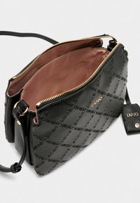 Schwarze synthetische Handtasche mit strukturiertem Oberflächen, ausgestattet mit einem Reißverschluss und goldfarbenen Beschlägen. Innenfutter aus hellbraunem Stoff.