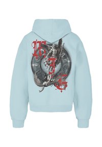 Lys blå hættetrøje med et stort grafisk motiv på ryggen, der viser en detaljeret sort-hvid illustration med røde accenter og stilet tekst.