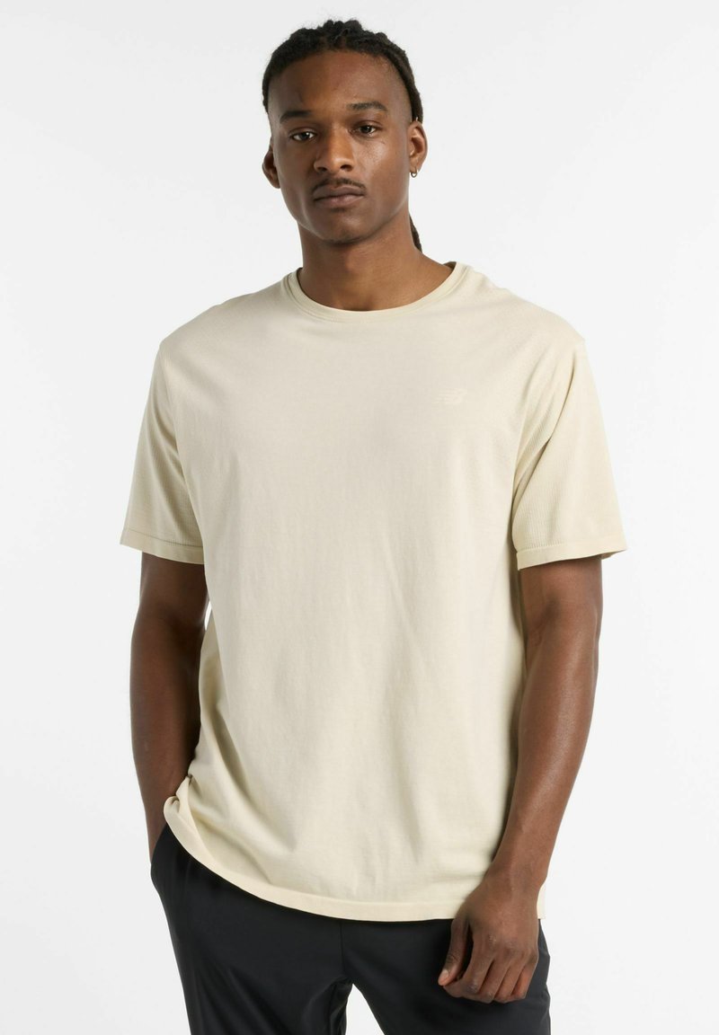 Cream-colored short-sleeve t-shirt with a relaxed fit, featuring a rounded neckline and subtle logo detail on the chest.