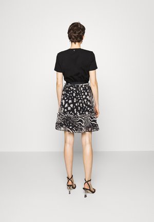 Czarny t-shirt zestawiony z rozkloszowaną spódnicą w czarno-biały wzór zwierzęcy. Noszone z czarnymi sandałkami na szpilce.