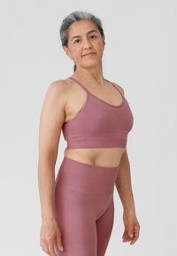 Licht mauve sportbeha en high-waisted legging gemaakt van rekbare stof. Het ontwerp heeft slanke banden en een gladde textuur.