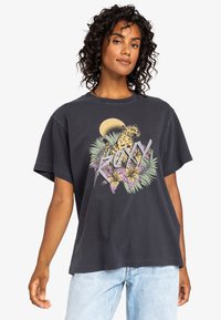 T-shirt nera oversize in cotone, con una grafica colorata di un leopardo e fiori, maniche corte e collo rotondo.