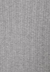 Textil gris claro con rayas verticales y pequeños patrones decorativos. Textura suave con un acabado sutil tejido a mano.