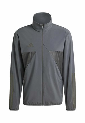 Harmaa urheilujakku, jossa on korkea kaulus, vetoketjullinen etuosa ja erottuva tummanharmaa paneeli. Sisältää Adidas-logon ja viistetyt sivutaskut.