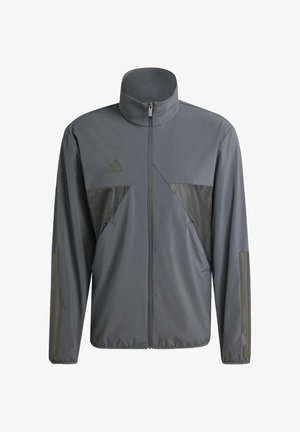 Harmaa urheilujakku, jossa on korkea kaulus, vetoketjullinen etuosa ja erottuva tummanharmaa paneeli. Sisältää Adidas-logon ja viistetyt sivutaskut.