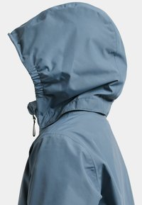 Αδιάβροχο μπουφάν σε ανοιχτό γαλάζιο με κουκούλα, που διαθέτει ραφές με πιέτες και κορδόνι για ρύθμιση. Λείο, ματ υλικό.