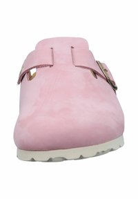 Zoccolo in pelle scamosciata rosa con due cinturini regolabili, lati aperti e suola in gomma bianca, caratterizzato da una texture liscia e un design minimalista.