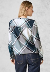 Maglietta a maniche lunghe con un motivo plaid multicolore che include blu, nero, bianco e verde acqua, realizzata in tessuto leggero.