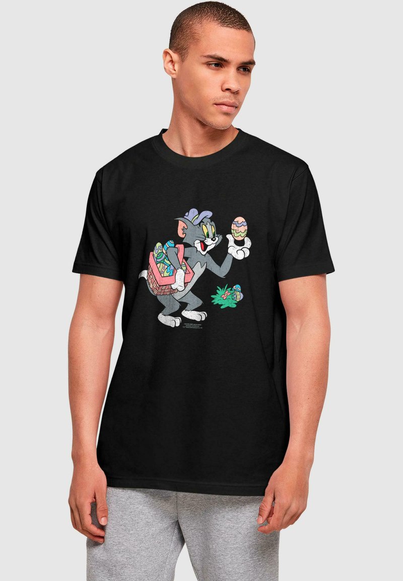 Black cotton t-shirt featuring a cartoon character holding Easter eggs, with a colorful basket on its back. Classic, vibrant graphic design.