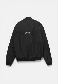 Čierna dlhá bunda s rukávmi s rebrovanými manžetami a spodným okrajom, s malým bielym štýlovým textom umiestneným v strede na hornej časti chrbta.