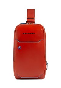 Mochila sintética roja con forma rectangular, acentos azules, bolsillo delantero con cremallera y correa ajustable. Logo visible en la parte superior.