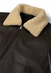 Brown leather jacket with a fluffy beige shearling collar and front zipper, featuring a smooth texture and minimal hardware details.
