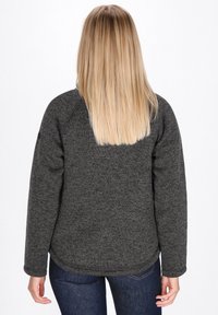 Temno siva flis pulover s teksturirano površino, okroglim izrezom in dolgimi rokavi, v kombinaciji z modrimi jeans hlačami. Zadnji pogled.